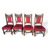 A set of four Arts and Crafts oak dining chairs, carved top rail, stuffed upholstery in maroon,