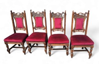 A set of four Arts and Crafts oak dining chairs, carved top rail, stuffed upholstery in maroon,