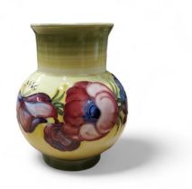 A Moorcroft  Anemone vase, tube lined with large flowerheads on a on mottled yellow and green