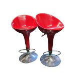 A pair of red vacuum formed and chrome bar stools