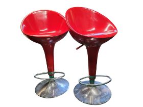 A pair of red vacuum formed and chrome bar stools