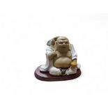 A Chinese pottery figure, of a Budai, holding a lotus, 13cm high, hardwood base