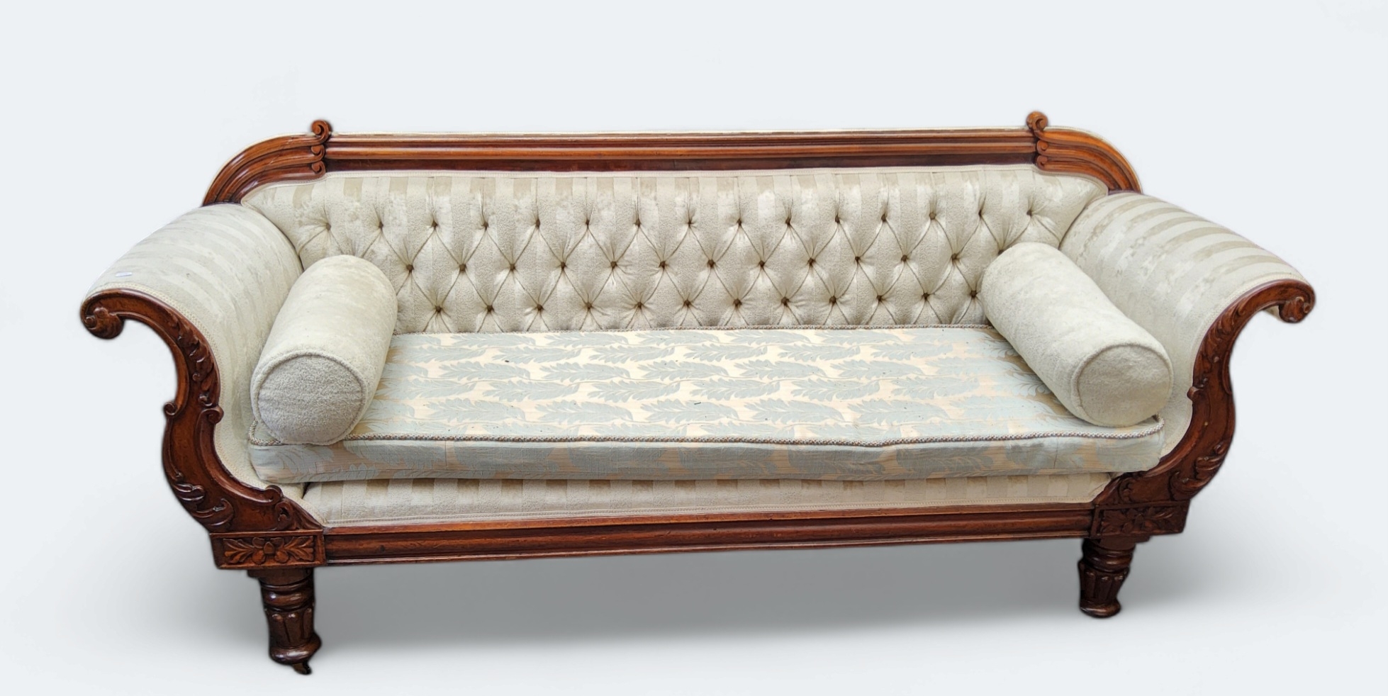 A Victorian mahogany scroll end sofa, upholstered in cream, turned legs. caster feet