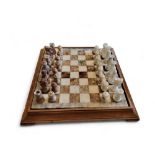 An onyx chess set, travertine and white, 44cm wide