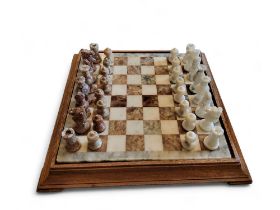 An onyx chess set, travertine and white, 44cm wide