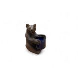 A novelty  Black Forest bear table vesta, seated, holding a blue well, 9cm high