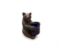 A novelty  Black Forest bear table vesta, seated, holding a blue well, 9cm high