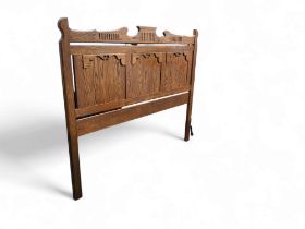 An Arts & Crafts type oak king size bed head, shaped cresting rail, three crossbanded panels,