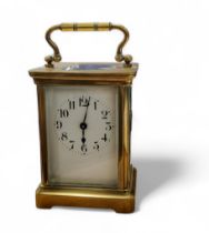 A 19th century French brass carriage clock, Arabic numerals, bevel glass panels, swing handle,