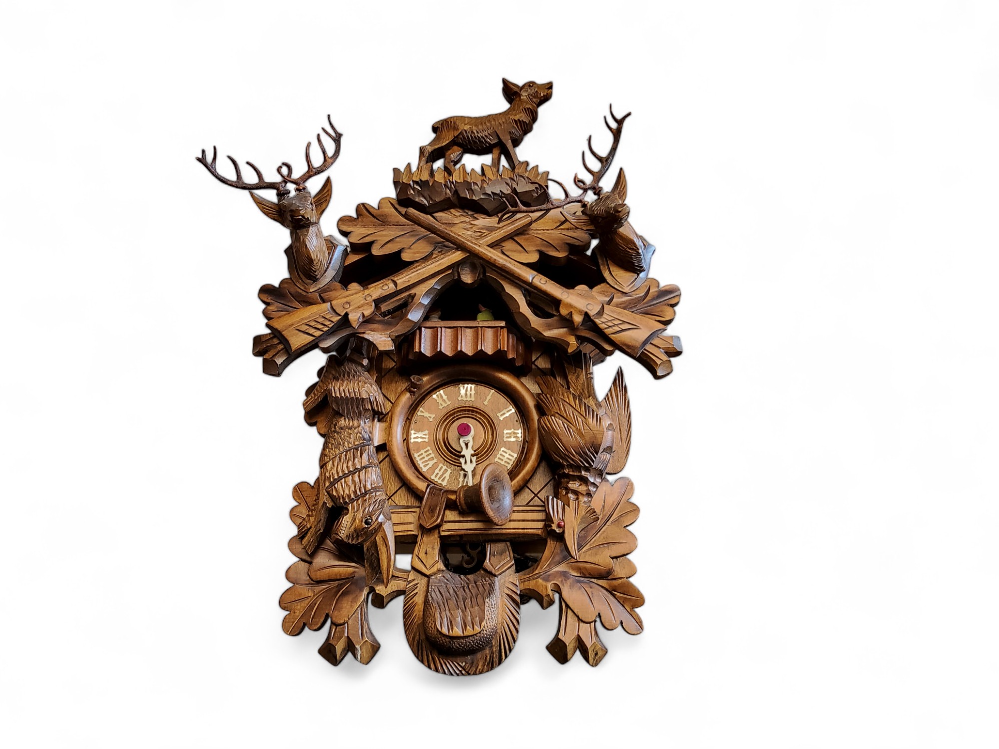 A Black Forest cuckoo clock, 9cm dial applied with Roman numerals, the case carved with dead game,