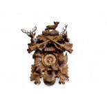 A Black Forest cuckoo clock, 9cm dial applied with Roman numerals, the case carved with dead game,