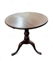 A George III mahogany one piece tilt top table, turned supports, tripod base, pad feet.72cm high,