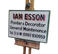 A mid 20th century signwritten advertisement board 'Ian Esson Painter & Decorator', green cushion