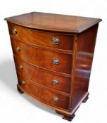 A reproduction mahogany and walnut bow fronted chest of drawers, four long cock beaded drawers,