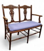An Edwardian mahogany two-seater salon sofa, pierced urnular splats, turned legs with turned