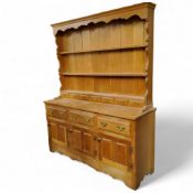 A modern limed oak kitchen dresser, oversailing ogee cornice above shaped sides holding g three