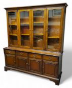 A reproduction Stag style display cupboard, ogee cornice above four glazed cupboards holding
