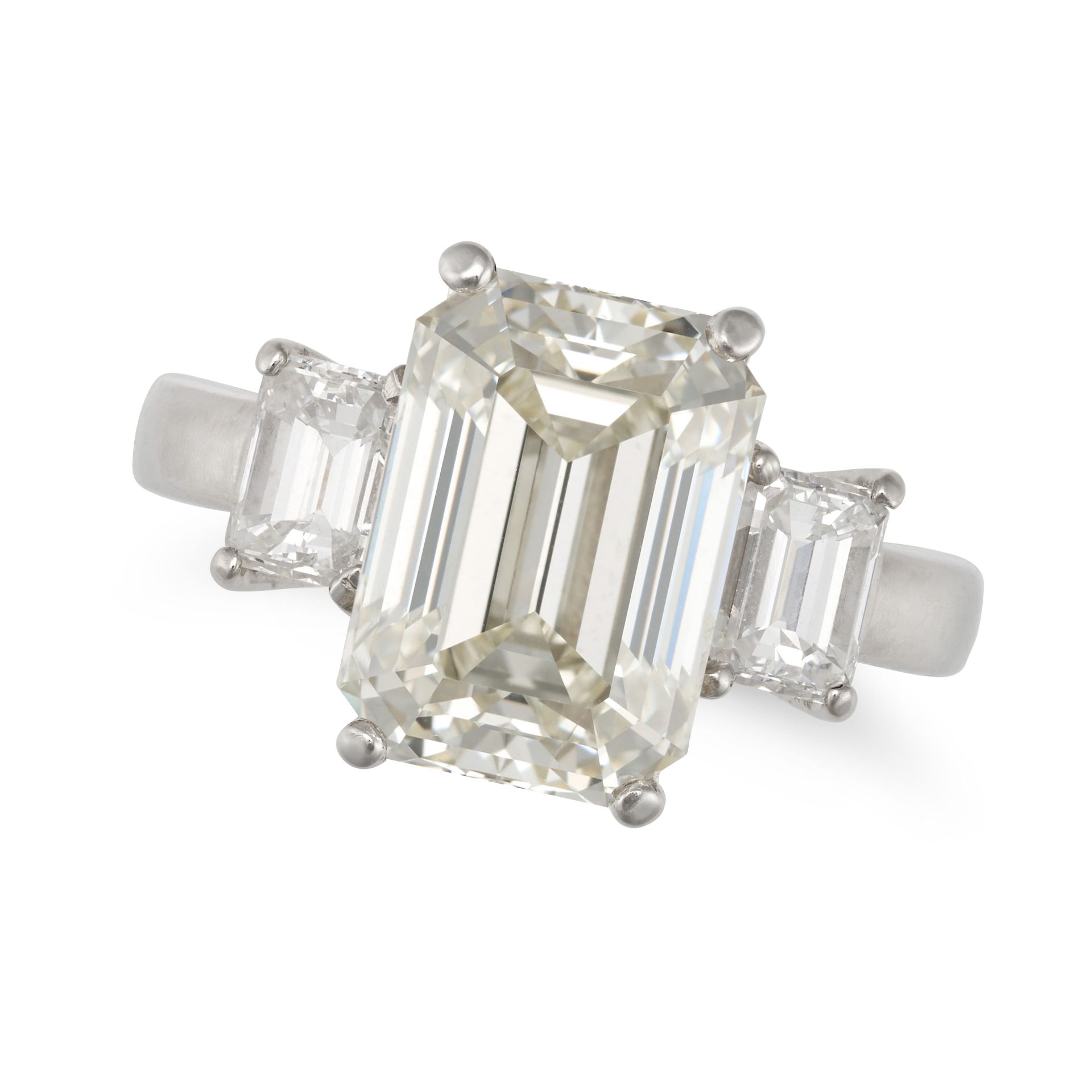 A DIAMOND THREE STONE RING in platinum, set with an emerald cut diamond of 5.33 carats between tw...