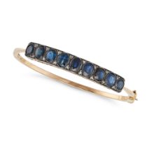 A SAPPHIRE AND DIAMOND BANGLE the hinged bangle set with a row of oval cut sapphires accented by ...