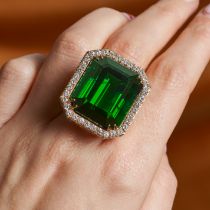 A GREEN TOURMALINE AND DIAMOND COCKTAIL RING set with an octagonal step cut green tourmaline of a...