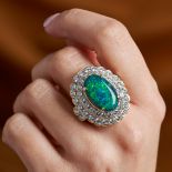 A BLACK OPAL AND DIAMOND CLUSTER RING set with an oval cabochon black opal of approximately 7.23 ...