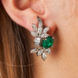 A PAIR OF EMERALD AND DIAMOND EARRINGS each set with an oval cut emerald accented by a spray of m...