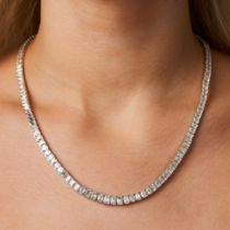A DIAMOND LINE NECKLACE comprising a row of graduating emerald cut diamonds, the diamonds all tot...