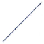 A SAPPHIRE AND DIAMOND LINE BRACELET comprising a row of oval cut sapphires accented by pairs of ...