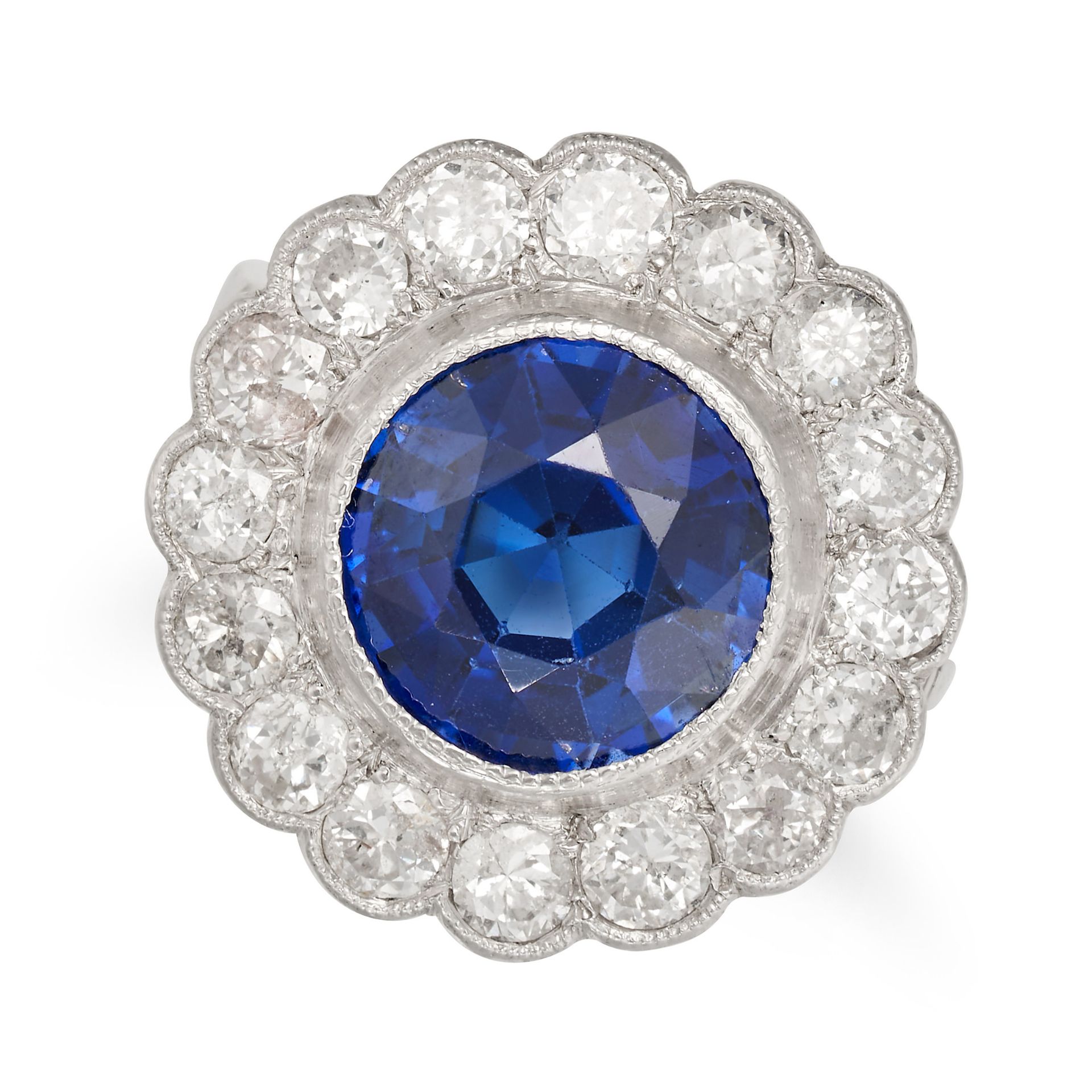 A SYNTHETIC SAPPHIRE AND DIAMOND CLUSTER RING set with a round cut synthetic sapphire in a cluste...