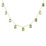 A PERIDOT FRINGE NECKLACE comprising a trace chain suspending nine fancy cut peridot pendants, st...