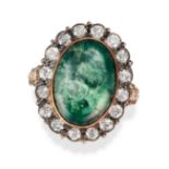 AN EMERALD AND DIAMOND CLUSTER RING in yellow gold and silver, set with an oval cabochon emerald ...