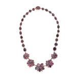 AN ANTIQUE GARNET FLOWER NECKLACE comprising a row of oval cut garnets, set with five floral moti...