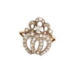AN ANTIQUE DIAMOND HORSESHOE RING in yellow gold and silver, designed as two interlocking horsesh...