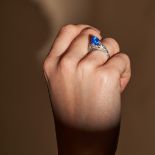 AN ART DECO KASHMIR SAPPHIRE AND DIAMOND RING in platinum, set with a sugarloaf cabochon sapphire...