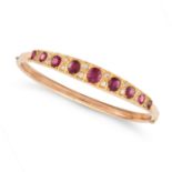 A RUBY AND DIAMOND BANGLE the hinged bangle set with a row of cushion cut rubies accented by rose...