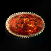 A 9 CARAT YELLOW GOLD AND AMBER OVAL BROOCH