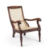 A 19TH CENTURY CEYLONESE CARVED HARDWOOD AND CANEWORK PLANTATION CHAIR