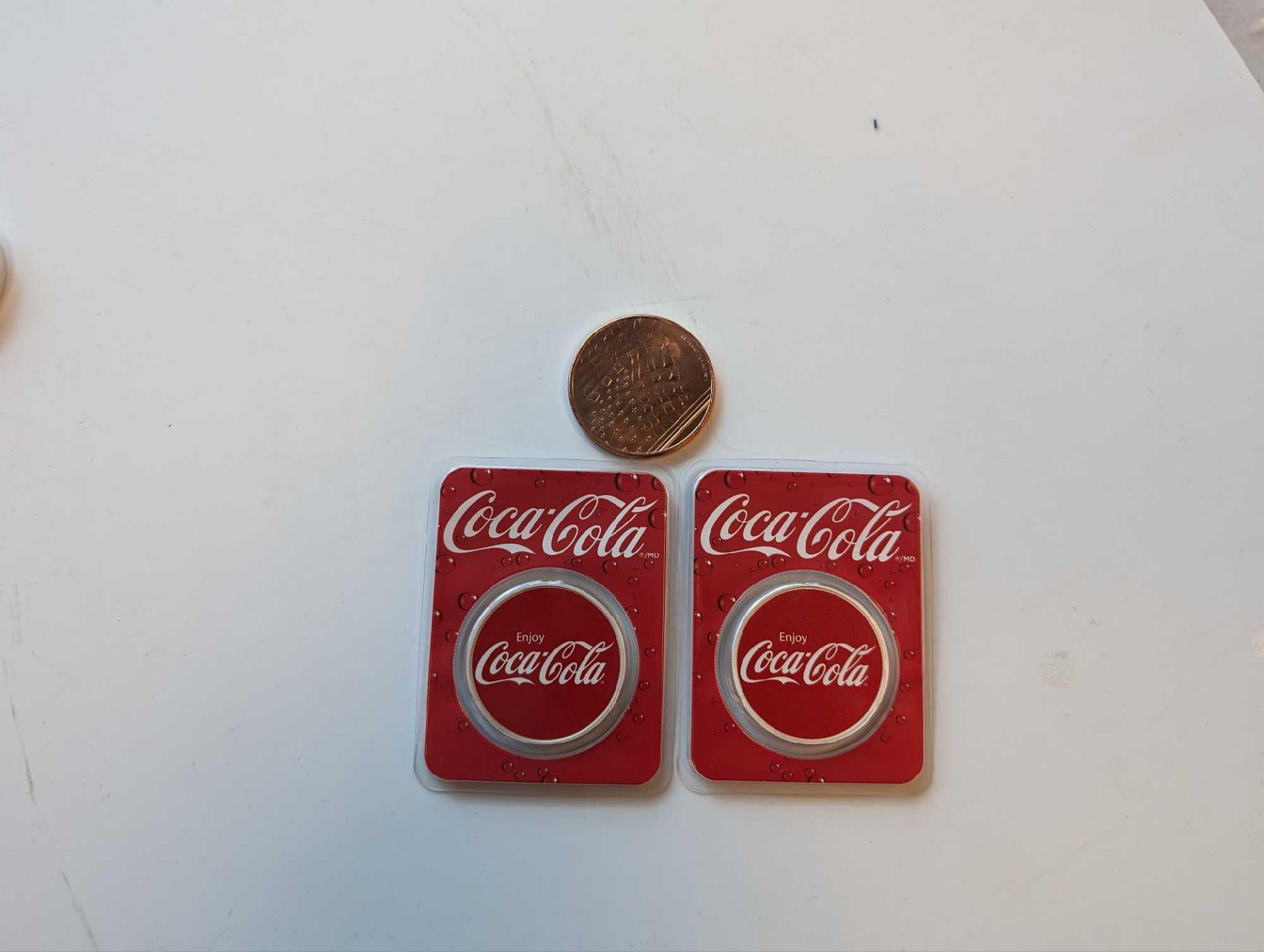 two silver Coca-Cola coins with copper American flag coin