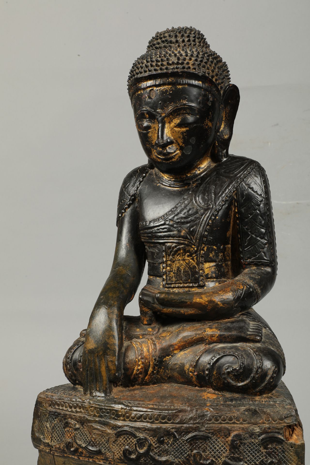 Buddha maravijaya assis en Bumishparsha Mudra sur un haut socle , vêtu d’une robe monastique
