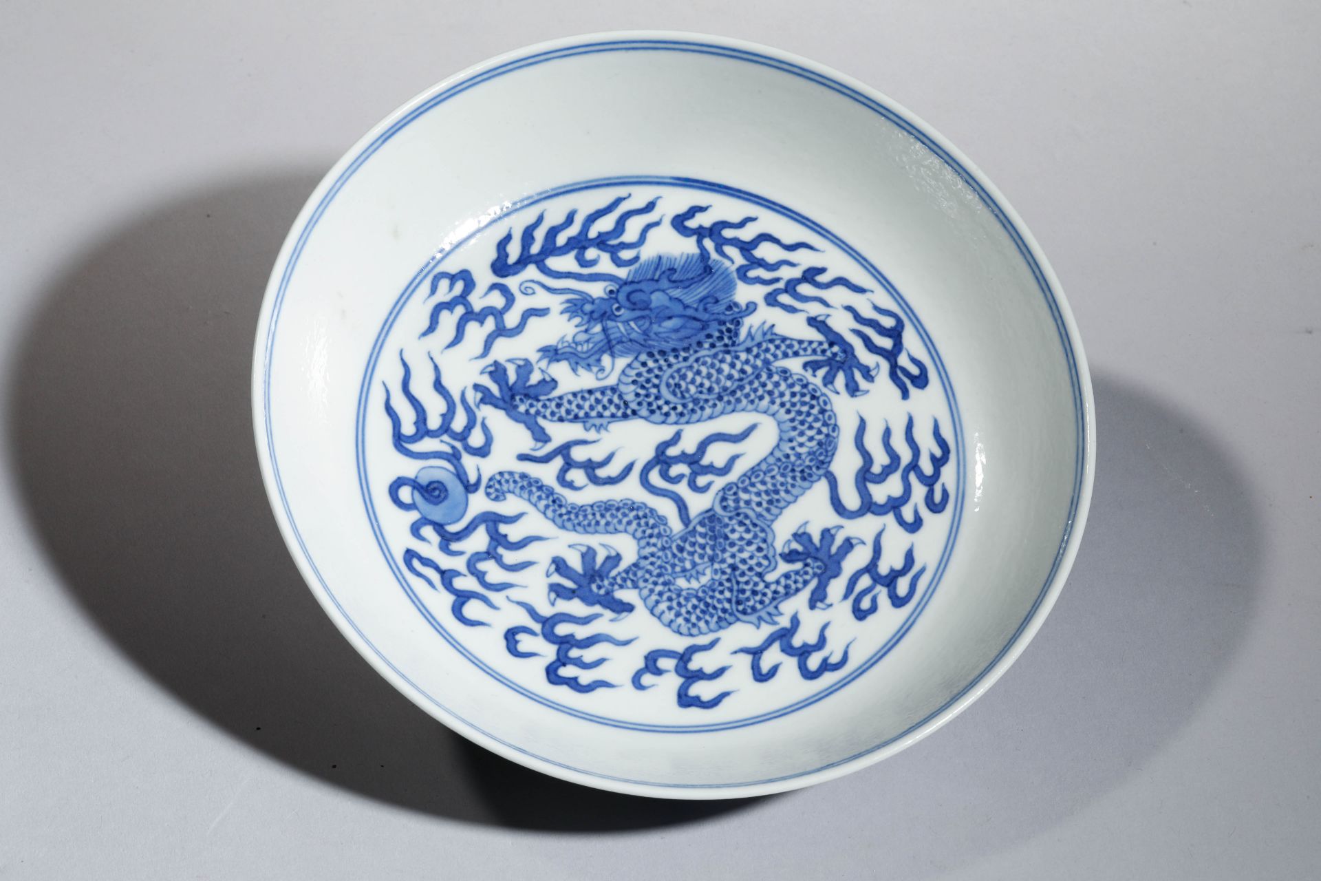 Rare coupe en porcelaine blanche à décor en bleu cobalt sous couverte de dragon Impérial en fond