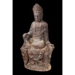 Kwan Yin, le Boddhisattva de la compassion assis en délassement sur une base rocailleuse, vêtu d’une