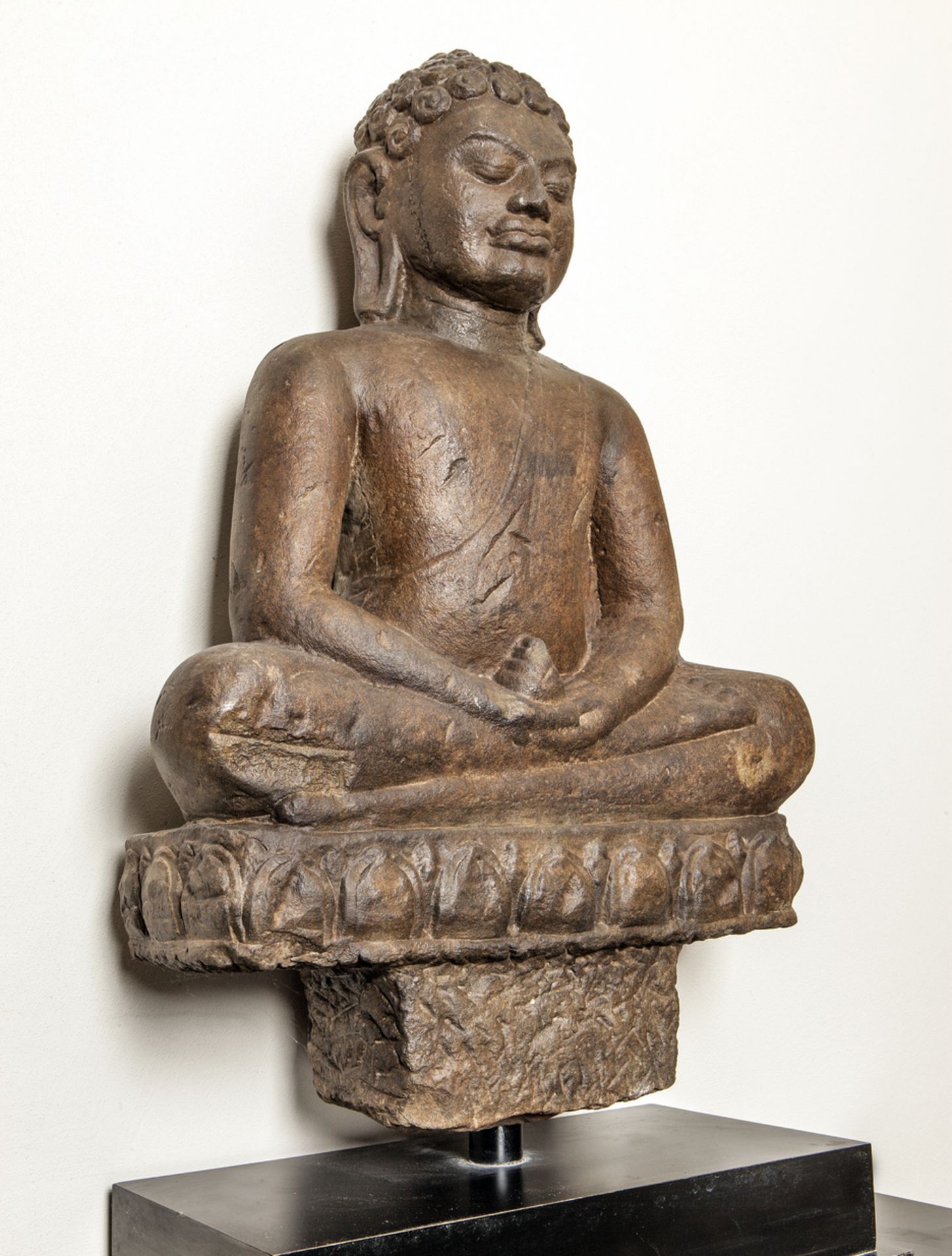 Bouddha assis en dhyanasana sur un socle à frise lotiforme les deux mains posées à plat tenant une