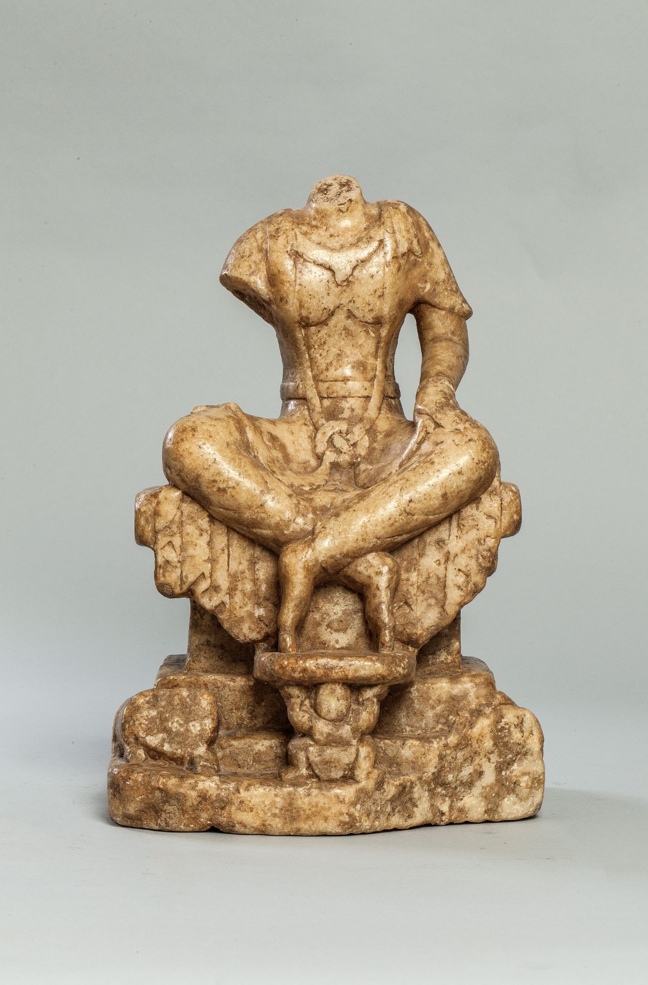 Buddha acéphale vêtu d'une robe monastique plissée et nouée dans son giron assis sur un trône les
