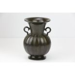 Vase à panse ovoïde godronnée, sur piédouche à large col évasé, sertie de deux anses à l ‘épaulement