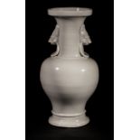 Vase balustre en porcelaine blanc de chine moulé au col de deux têtes de chimères tenant des anneaux