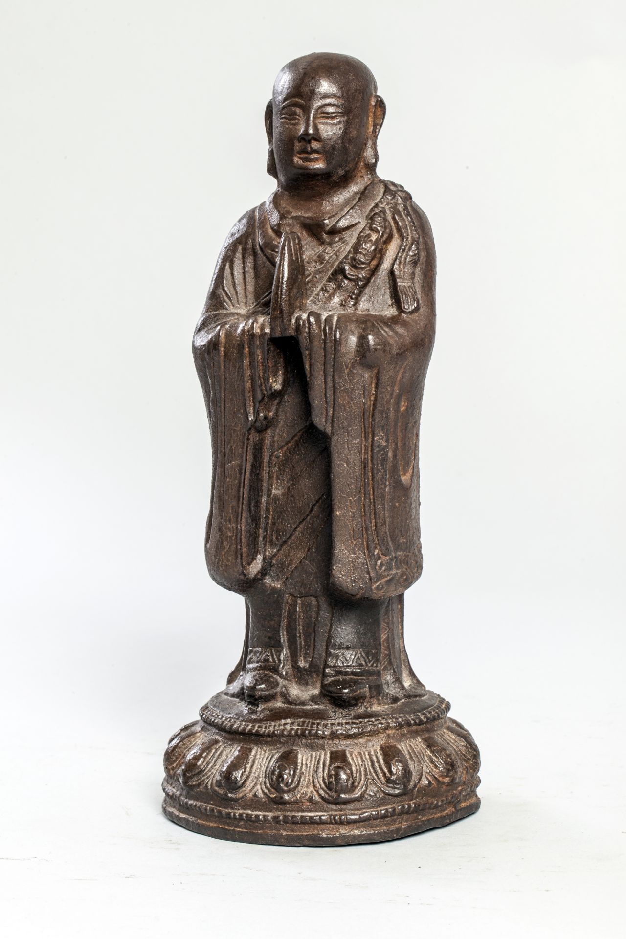 Lohan figuré debout sur une base lotiforme vêtu d'une robe monastique en adoration Fonte de fer