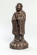 Lohan figuré debout sur une base lotiforme vêtu d'une robe monastique en adoration Fonte de fer