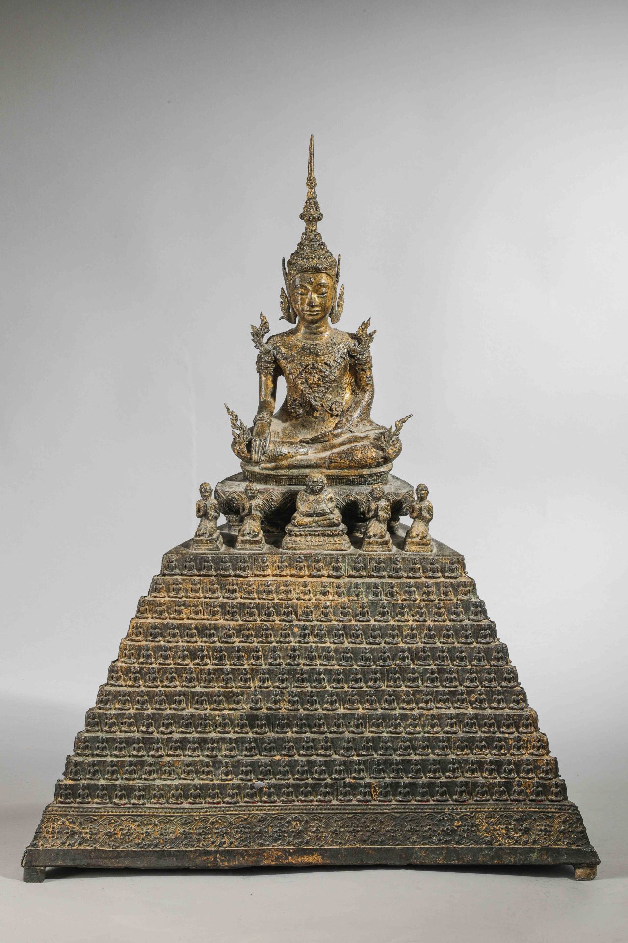 Buddha Maravijaya assis en Bumishparsha mudra sur un haut socle étagé, quatre adorant et un Putaï