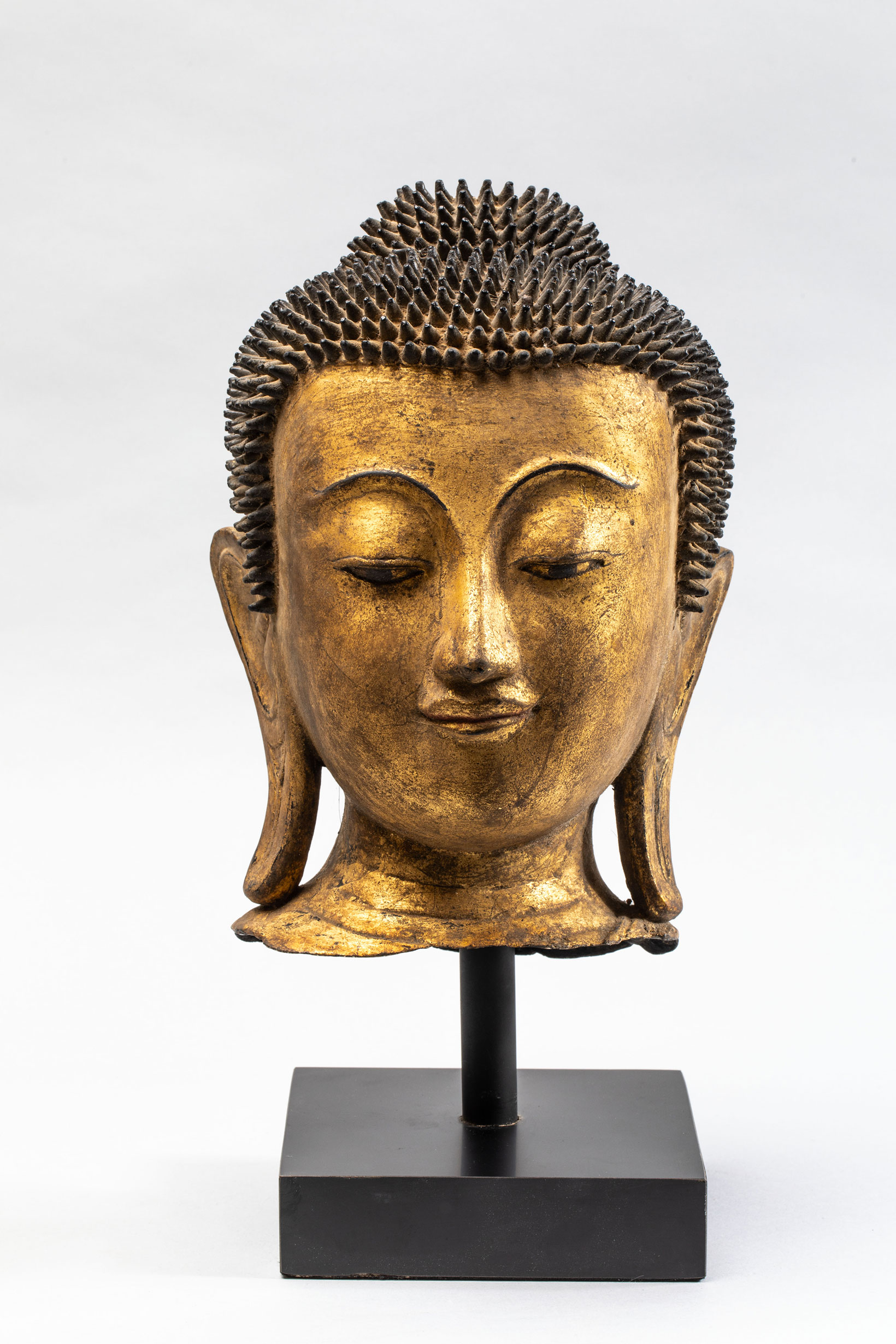 Tête de Buddha coiffée de fines bouclettes hérissées surmontée de la protubérance crânienne ushnisha