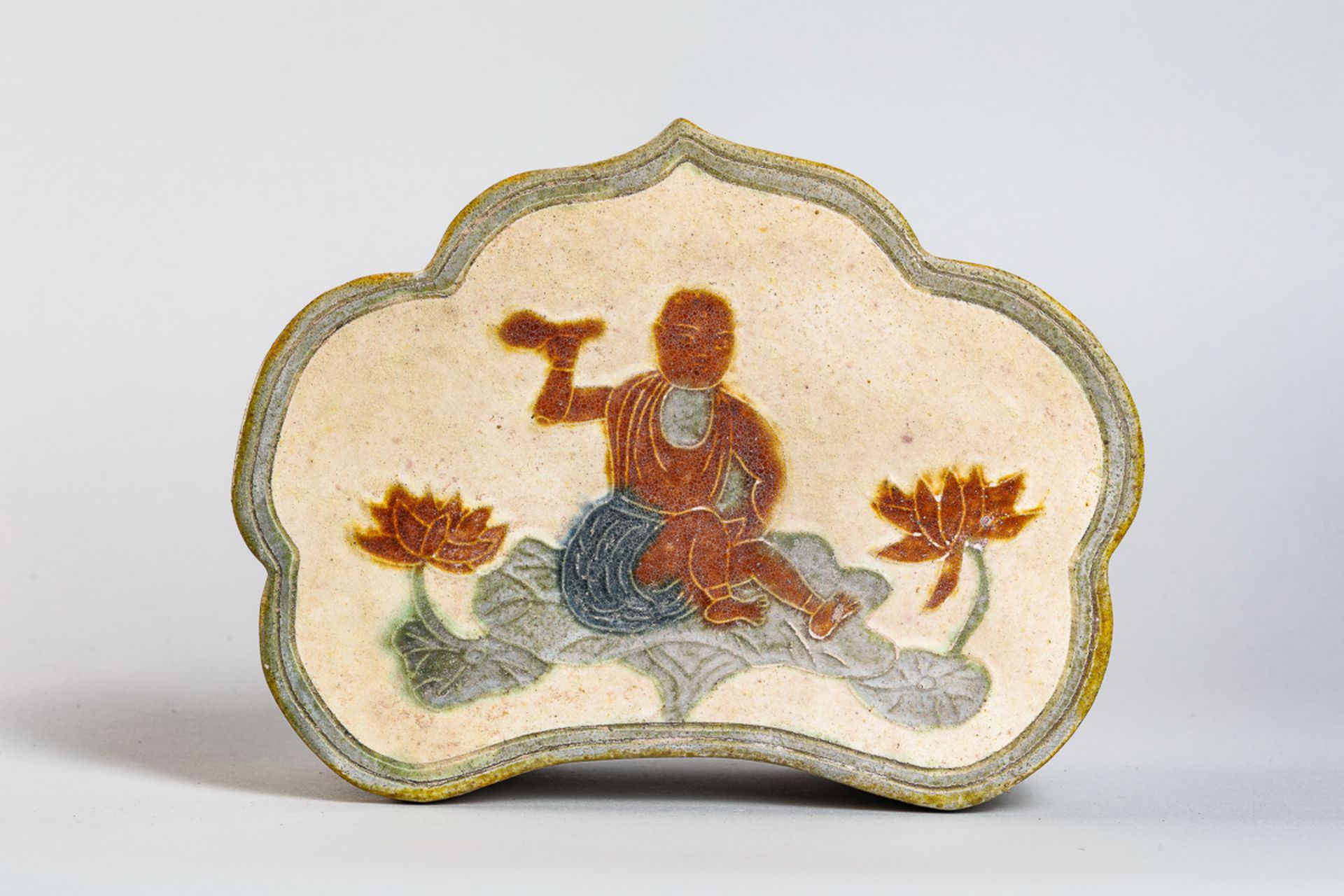 Repose tête "sancaï" de forme polylobé, en grès emmaillé trois couleurs, décoré d'un Lohan